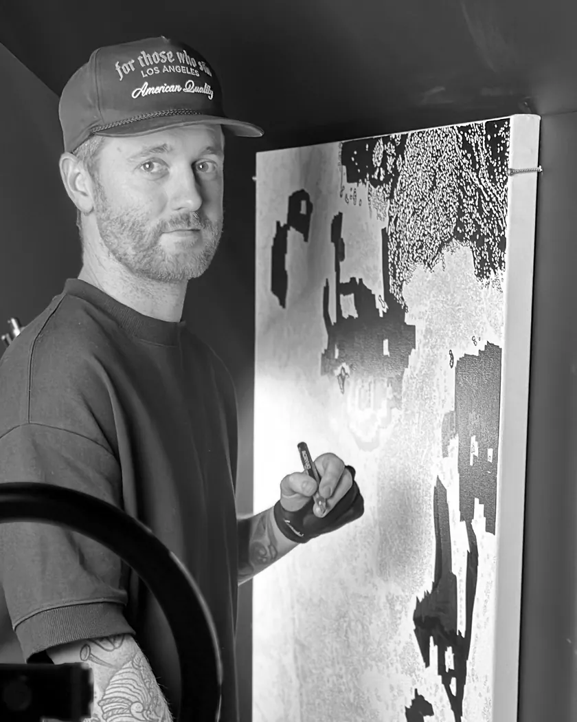 Sam at work on a large canvas in his studio, pen in hand, in black and white