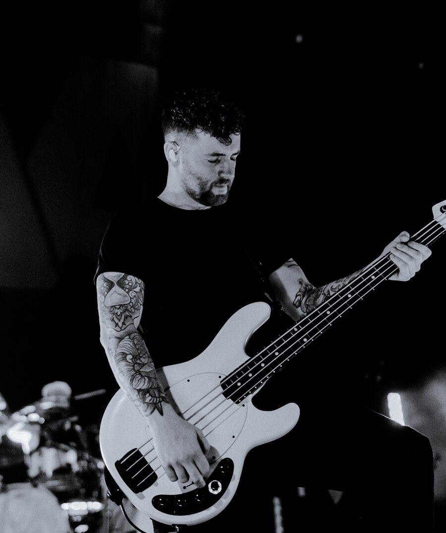 Sam Bettley performing on stage with Asking Alexandria