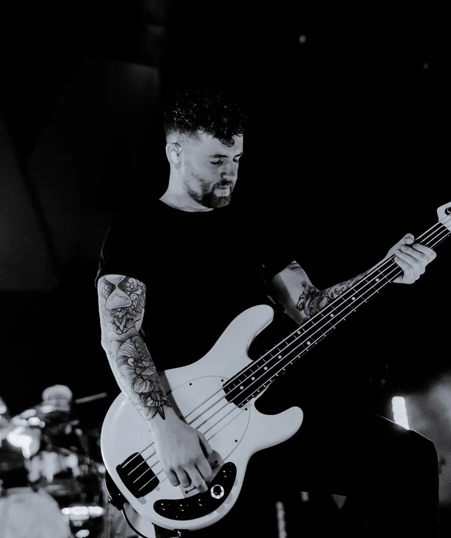 Sam Bettley playing bass on stage, in black and white
